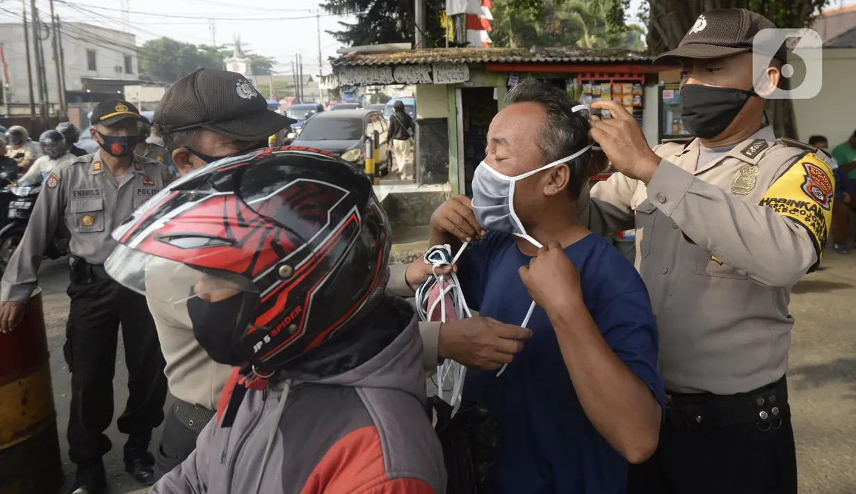 Anggota polisi dari Polsek Parung membantu memasangkan masker kepada pengendara sepeda motor di depan Polsek Parung, Kabupaten Bogor, Jawa Barat, Rabu (2/9/2020). Pembagian masker gratis ini untuk mengajak masyarakat hidup sehat dan mencegah penular COVID-19. (merdeka.com/Dwi Narwoko)
