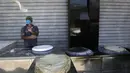 Seorang pria mengenakan masker saat membuat roti selama bulan suci Ramadan di sebuah toko di Kota Gaza, Palestina, Jumat (1/5/2020). (MOHAMMED ABED/AFP)