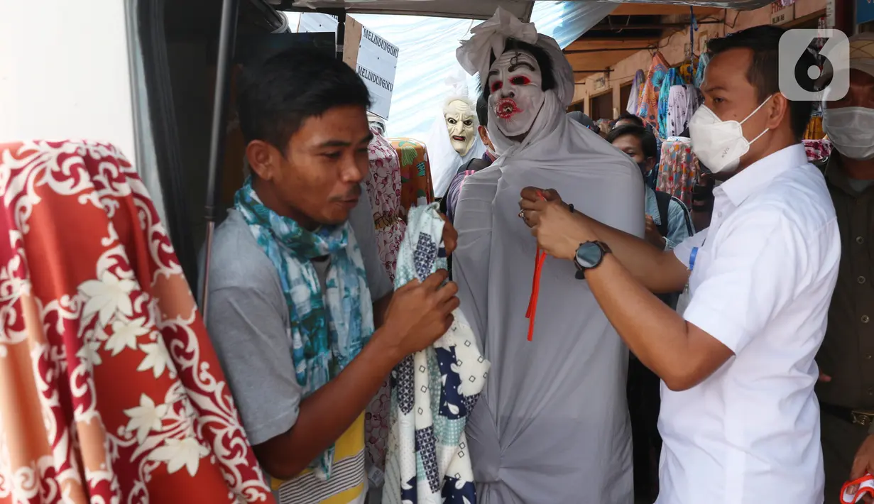 Petugas Kecamatan Larangan berkeliling mengenakan pakaian pocong saat melakukan sosialisasi di Pasar Cipadu, Kota Tangerang, Rabu (16/9/2020). Pocong ini bentuk sosialiasi agar warga memperhatikan perilaku 3M COVID, yaitu memakai masker, menjaga jarak dan mencuci tangan. (Liputan6.com/Angga Yuniar)