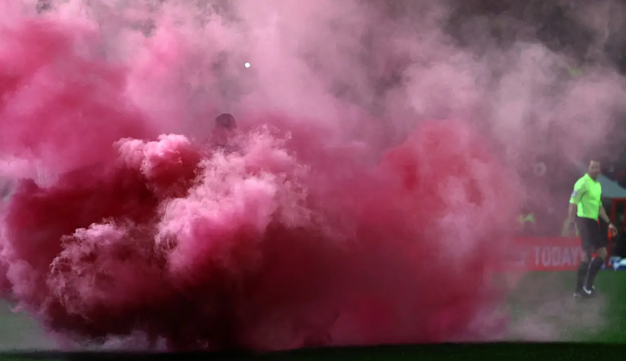 Laga Swindon Town kontra Manchester City pada putaran ketiga Piala FA 2021/22 yang berlangsung di Country Ground diwarnai dengan smoke bomb. Hal tersebut terjadi saat Harry McKirdy mencetak gol pertama dan satu-satunya untuk The Robins. (AFP/Adrian Dennis)