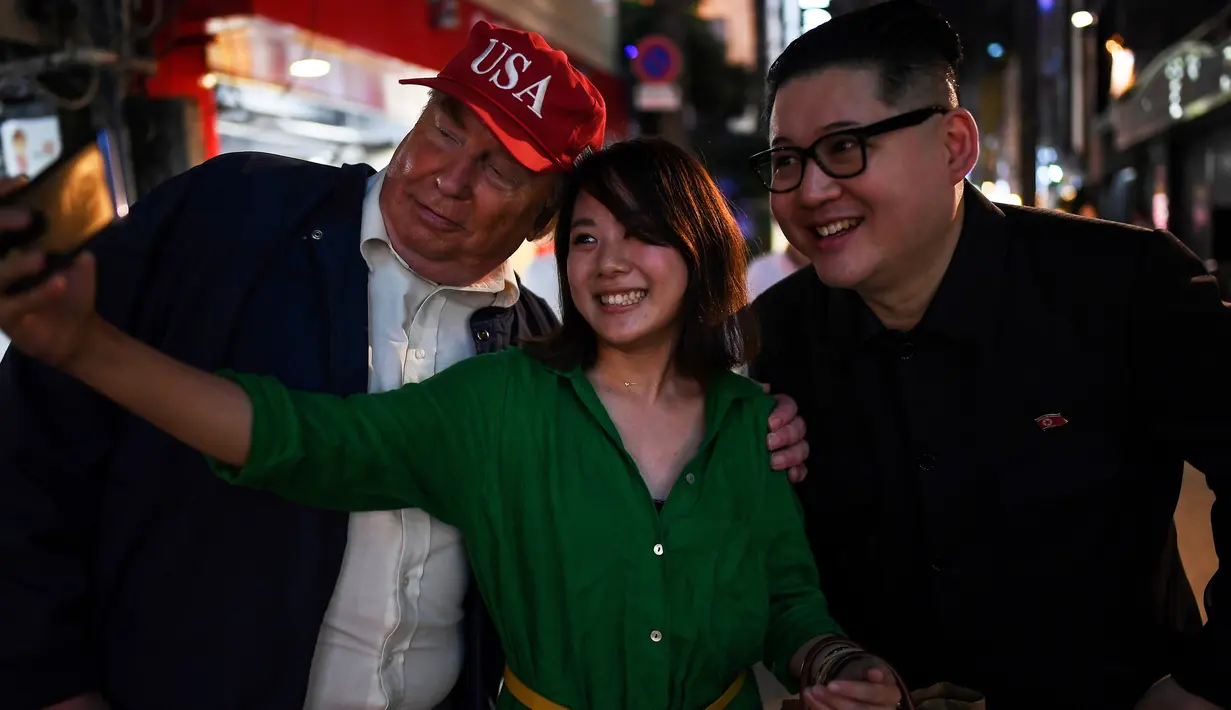 Seorang wanita berswafoto dengan peniru pemimpin Korea Utara Kim Jong-un dan peniru Presiden AS, Donald Trump selama gelaran KTT G20 di Osaka, Jepang, Jumat (28/6/2019). Sejumlah pemimpin dunia berkumpul dalam KTT G20 yang berlangsung dua hari di Osaka. (Charly TRIBALLEAU/AFP)