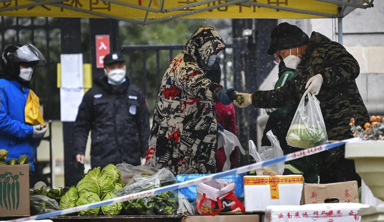 Warga membeli produk dari pasar sementara di pintu masuk area perumahan yang dikarantina, Kota Xi'an, Provinsi Shaanxi, China, 25 Desember 2021. Xi'an lockdown ketat dengan hanya satu orang per rumah tangga yang diizinkan keluar setiap dua hari untuk berbelanja kebutuhan. (Tao Ming/Xinhua via AP)