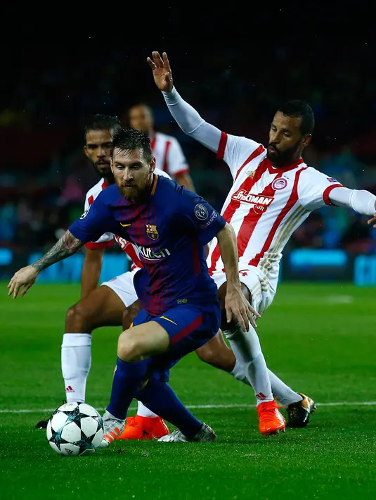 Penyerang Barcelona, Lionel Messi mengendalikan bola dengan kawalan pemain Olympiakos, Omar Elabdellaoui dalam fase grup Liga Champions di Camp Nou Stadium, Kamis (19/10). 10 pemain Barcelona sukses melumat Olympiakos 3-1. (AP/Manu Fernandez)