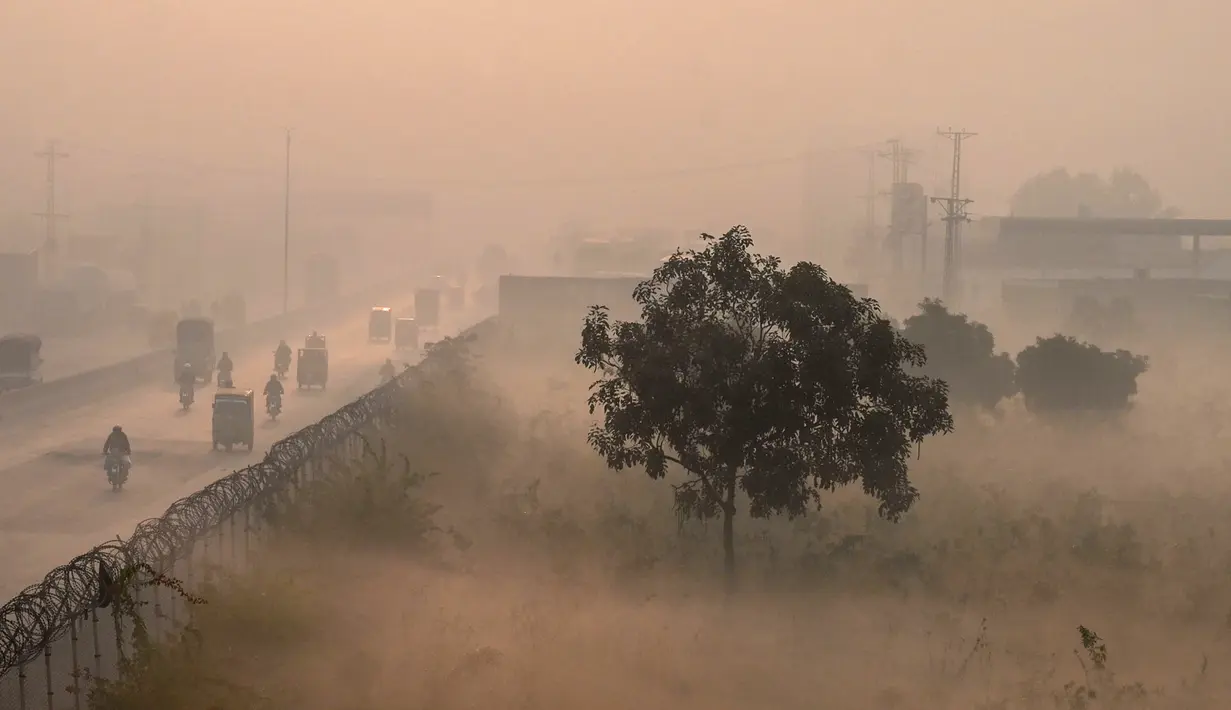 Orang-orang bepergian di sepanjang jalan di tengah kondisi kabut asap tebal di Lahore, Pakistan, Kamis (18/11/2021). Lahore telah dinyatakan sebagai kota dengan tingkat polusi udara tertinggi di dunia saat kabut asap beracun tebal melanda kota tersebut. (Arif ALI/AFP)