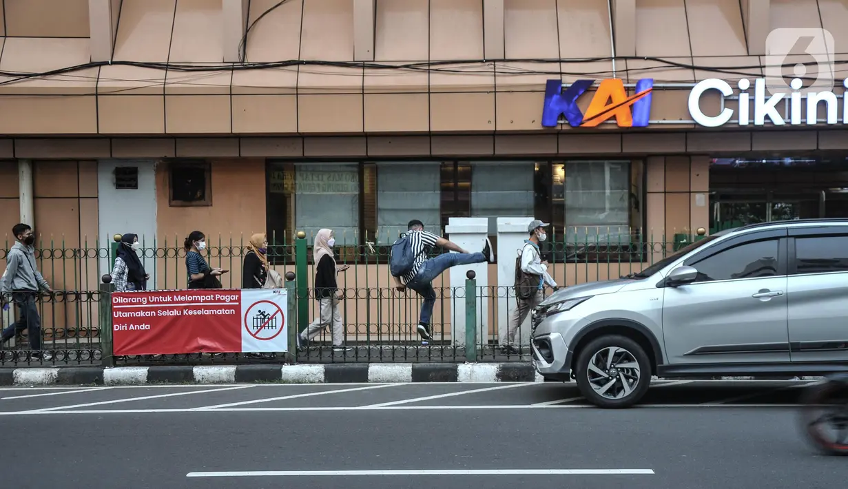 Calon penumpang kereta Commuter Line (KRL) melompati pagar saat hendak menuju Stasiun Cikini, Jakarta Pusat, Kamis (25/5/2023). (merdeka.com/Iqbal S.Nugroho)