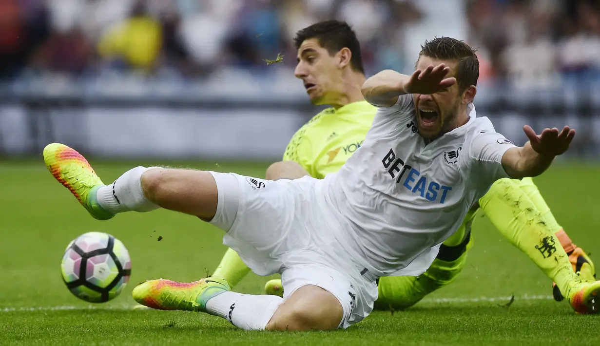 Aksi pemain Swansea City, Gylfi Sigurdsson saat berebut bola dengan kiper Chelsea, Thibaut Courtois pada lanjutan Premier League di Liberty Stadium,(11/9/2016) WIB. (Reuters/Rebecca Naden)