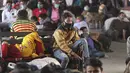 Orang-orang yang memakai masker sebagai antisipasi terhadap virus corona menunggu transportasi di terminal bus di Jammu, India (26/3/2021). Negara bagian Maharashtra tengah, tempat ibu kota keuangan India, Mumbai, menyumbang lebih dari separuh infeksi baru.  (AP Photo/Channi Anand)