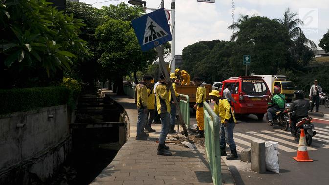 Petugas membongkar pagar pembatas besi di kawasan Pinang Ranti, Jakarta, Senin (11/2). Zebra cross yang berada di samping Tamini Square itu sempat jadi perbincangan lantaran terhalang oleh pagar besi hijau setinggi 1 meter. (Liputan6.com/Herman Zakharia)