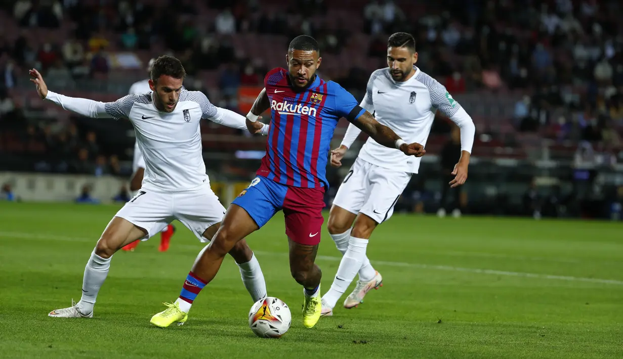 Penyerang Barcelona, Memphis Depay (tengah) mengontrol bola dibayangi pemain Granada pada lanjutan La Liga di Camp Nou, Selasa (21/9/2021) dini hari WIB. Barcelona dipaksa bermain imbang 1-1 oleh tamunya Granada. (AP Photo/Joan Monfort)