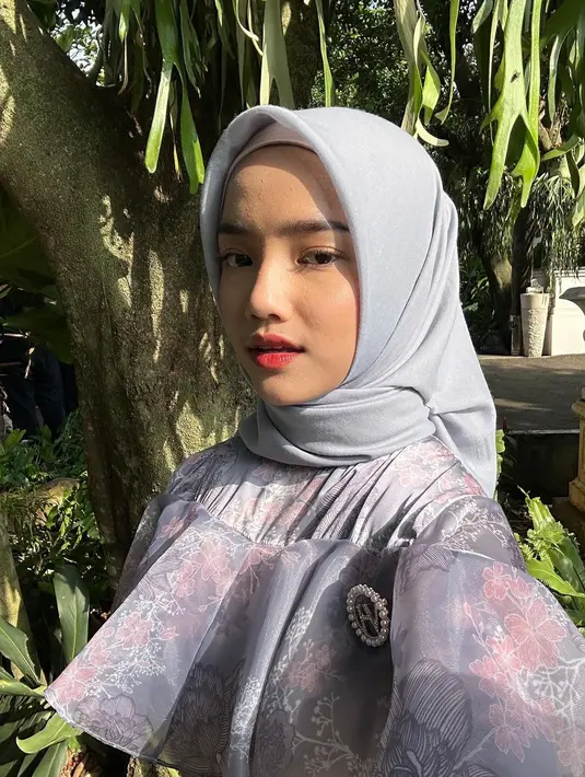 Dress bernuansa ungu tersebut dipadukan dengan hijab segi empat berwarna abu-abu yang diikat simpel ke belakang. @fuji_an.