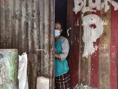 Warga mengintip dari pintu rumah saat pemberlakuan mikro lockdown di RW 002, Kelurahan Krukut, Taman Sari, Jakarta Barat, Senin (10/1/2022). Satgas COVID-19 Jakarta memberlakukan mikro lockdown di RT 08, 010, 011, dan 014 usai 36 warga terkonfirmasi positif COVID-19. (merdeka.com/Iqbal S. Nugroho)