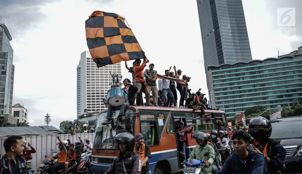 Suporter Persija Jakarta, Jakmania, melakukan pawai kemenangan Juara Piala Presiden di kawasan Bundaran HI, Minggu (18/2). Sepanjang jalan menuju Balai Kota dipenuhi lautan oranye dengan pekikan kemenangan dari Jakmania. (Liputan6.com/Faizal Fanani)