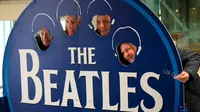 Wisatawan berpose disebuah papan Beatles di kafe kopi bertema The Beatles di Liverpool, , Inggris, (2/3). Warga Liverpool Peringati 50 tahun terakhir kali The Beatles melakukan konser di kota asal mereka ini. (REUTERS/Phil Noble)