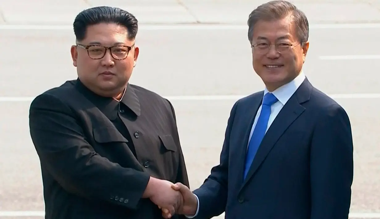Pemimpin Korea Utara Kim Jong-un dan Presiden Korea Selatan Moon Jae-in berjabat tangan untuk memulai pertemuan bersejarah mereka di atas garis demarkasi Zona Demiliterisasi (DMZ), Panmunjom, Jumat (27/4). (Korea Broadcasting System via AP)