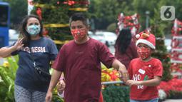 Warga DKI Jakarta melintas di dekat hiasan pohon Natal 2021 di Bundaran HI, Jakarta, Sabtu (25/12/2021). Libur Natal 2021 dimanfaatkan sebagian warga berfoto berlatar pohon Natal yang telah dihias atau berjalan-jalan ke mal untuk mengisi waktu berlibur bersama. (merdeka.com/Imam Buhori)