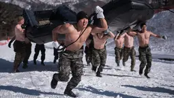 Gabungan tentara Korea Selatan dan AS mengangkat perahu karet saat latihan musim dingin di Pyeongchang, Korea Selatan (24/1). Mereka latihan dengan setengah telanjang untuk mengetes ketahanan fisik. (AFP/Ed Jones)