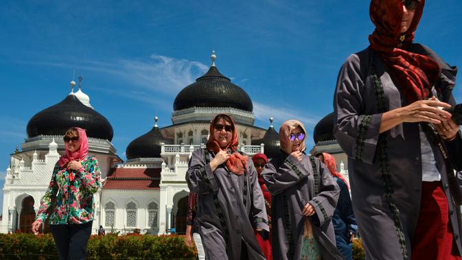 Turis asing mengenakan jilbab saat mengunjungi Masjid Agung Baiturrahman di Banda Aceh, Aceh pada 6 Agustus 2019. Selain sebagai tempat ibadah, Masjid Baiturahman juga menjadi tempat wisata bagi turis lokal dan mancanegara. (CHAIDEER MAHYUDDIN / AFP)