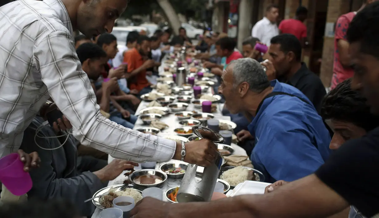 Di Kairo, Mesir, kaum muslim berbuka puasa pertama di bulan Ramadan di sebuah jalan yang menyajikan takjil secara cuma-cuma, (29/6/2014). (REUTERS/Asmaa Waguih)