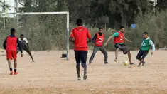 Sejumlah pria bermain sepak bola di lapangan tanah sebelum buka puasa selama bulan Ramadhan, di ibu kota Libya, Tripoli (24/4/2021). (AFP/Mahmud Turkia)