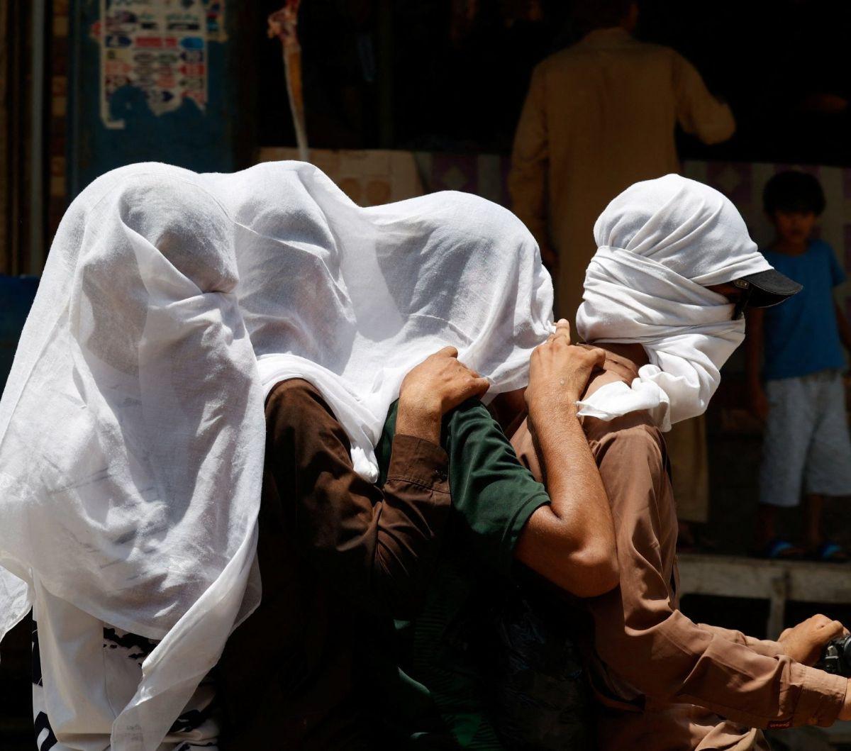 Sejumlah pria mengendarai sepeda motor sambil menutupi kepalanya dengan kain basah untuk menghindari terik matahari yang menyengat di Jacobabad, Provinsi Sindh, Pakistan, pada 26 Mei 2024. Suhu di Provinsi Sindh, Pakistan dilaporkan melonjak hingga 52 der