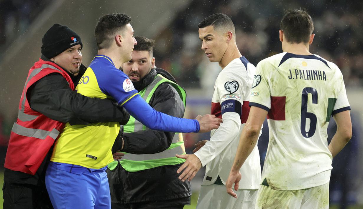 Petugas mengamankan seorang suporter yang berusaha mendekati pemain Portugal, Cristiano Ronaldo saat pertandingan melawan Luksemburg pada matchday kedua Grup J Kualifikasi Euro 2024 di Stadion Stade de Luxembourg, Senin (27/3/2023). (AP Photo/Olivier Matthys)