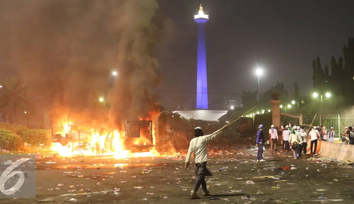 Sejumlah mobil dibakar pendemo saat terjadi bentrok dengan polisi di kawasan Monas, Jakarta, Jumat (4/11). Diduga bentrok terjadi saat massa HMI menyerang polisi dan polisi membalasnya dengan melempar gas air mata. (Liputan6.com/Immanuel Antonius)