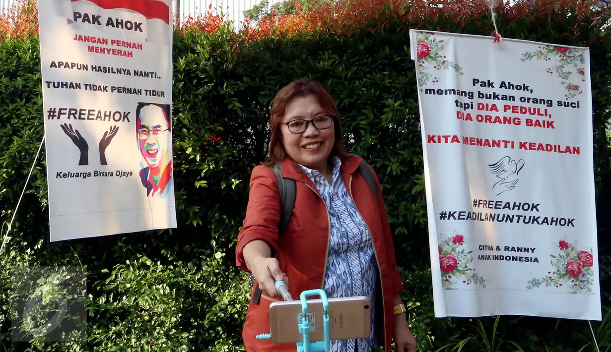 Seorang wanita berswafoto dengan latar belakang spanduk dukungan di halaman Balai Kota DKI Jakarta, Selasa (9/5). Menjelang sidang pembacaan putusan Basuki Tjahaja Purnama atau Ahok, kondisi pendopo Balai Kota tampak lengang. (Liputan6.com/Johan Tallo)