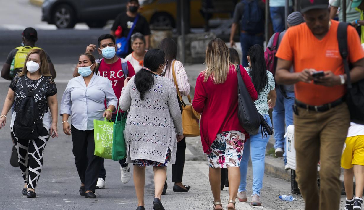 Orang-orang melintas di jalan pada hari pertama masker tidak lagi wajib di Panama City, Panama, Senin (11/7/2022). Masker tidak lagi diperlukan kecuali di rumah sakit dan transportasi umum. (AP Photo/Arnulfo Franco)