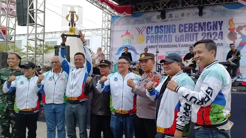 Camat Tarogong Kidul Kabupaten Garut Ahmad Mawardi, mengangkat piala bergilir sebagai juara umum Porkab Garut 2024. (Liputan6.com/Jayadi Supriadin)