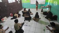 Sejumlah siswa belajar di lantai kelas di Madrasah Ibtidaiyah (MI) Misbahul Athfal, Kampung Cileuleuy, Desa Cibentang, Kecamatan Ciseeng, Bogor, Kamis (8/8/2019). Sekolah tersebut dibangun murni swadaya masyarakat  dengan jumlah siswa sebanyak 126 orang. (merdeka.com/Arie Basuki)