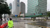 Suasana arus lalu lintas di Jalan MH Thamrin Simpang Kebon Sirih, Jakarta Pusat pada Minggu 1 Januari 2023 pagi terpantau lengang dan diguyur hujan gerimis. (Foto: Twitter @TMCPoldaMetro)