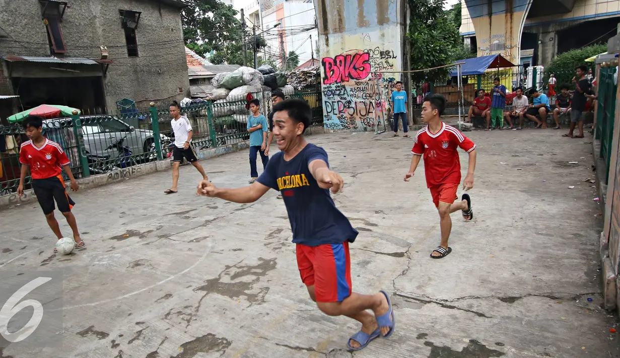 Ekspresi salah satu remaja saat bermain sepak bola di kolong rel kereta kawasan Juanda, Jakarta, Jumat (27/5). Tidak tersedianya ruang terbuka menyebabkan lahan tersebut dijadikan tempat bersosialisasi bagi warga. (Liputan6.com/Immanuel Antonius)