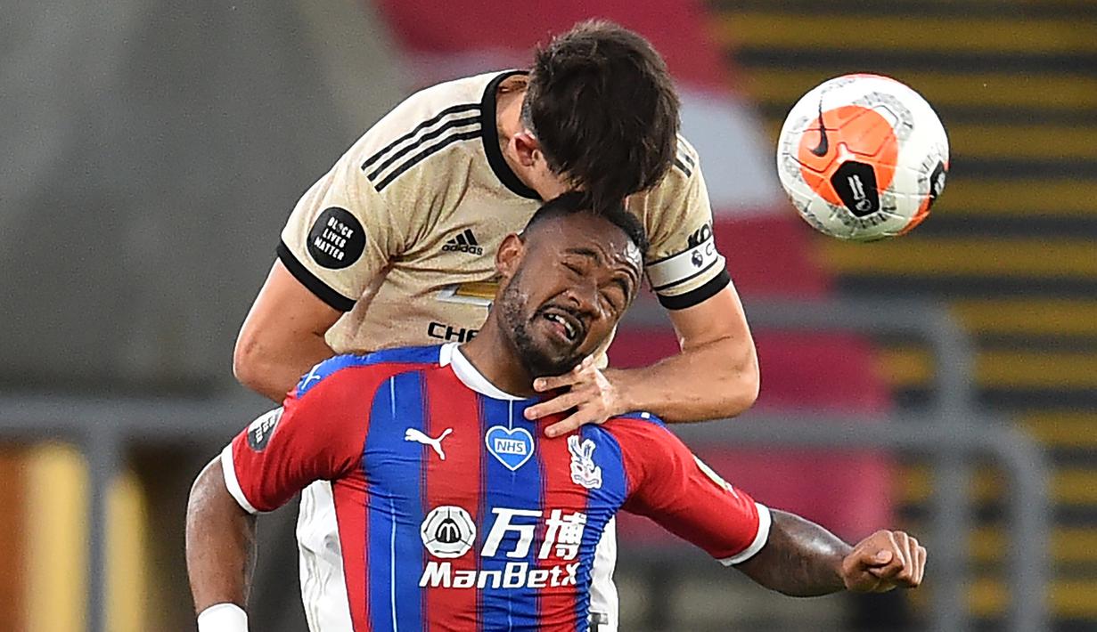 Bek Manchester United, Harry Maguire, berebut bola dengan striker Crystal Palace, Jordan Ayew, pada laga lanjutan Premier League di Selhurst Park, Jumat (17/7/2020) dini hari WIB. Manchester United menang 2-0 atas Crystal Palace. (AFP/Glyn Kirk)