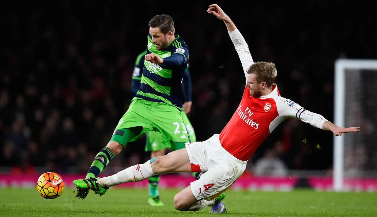 Gelandang Swansea City, Gylfi Sigurdsson (kiri) berusaha melewati bek Arsenal, Per Mertesacker pada lanjutan liga Inggris di Stadion Emirates (2/3). Swansea menang atas Arsenal dengan skor 2-1. (Reuters/Dylan Martinez)
