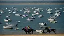 Peserta memacu kudanya saat mengikuti lomba pacuan kuda pantai tahunan di Sanlucar de Barrameda, dekat Cadiz, Spanyol (17/8). Pacuan kuda ini bermula dari para nelayan yang berlomba mengangkut tangkapan mereka melalui pantai. (AFP Photo/Cristina Quicler)