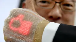 Seorang pria menunjukkan layar elastis ultra tipis yang dilengkapi dengan dioda di Tokyo, Jepang (14/2). Alat ini dapat menerima pesan, termasuk emoji dan dapat memantau kesehatan penggunanya. (AFP Photo/Toru Yamanaka)
