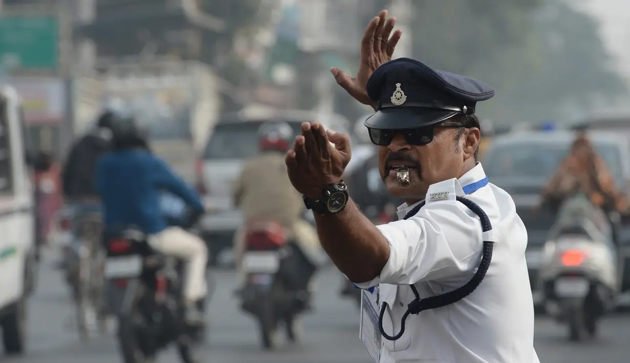 Polisi lalu lintas India Ranjeet Singh melakukan gerakan seperti tarian saat mengarahkan lalu lintas di persimpangan Indore, India (22/12). (AFP Photo/Indranil Mukherjee)