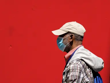 Seorang pejalan kaki yang mengenakan masker berjalan di Philadelphia, Jumat (22/4/2022). Kota itu meninggalkan mandat masker dalam ruangan pada hari Jumat, hanya beberapa hari setelah menjadi kota metropolitan AS pertama yang menerapkan kembali wajib masker sebagai tanggapan atas peningkatan kasus COVID-19 dan rawat inap. (AP Photo/Matt Rourke)