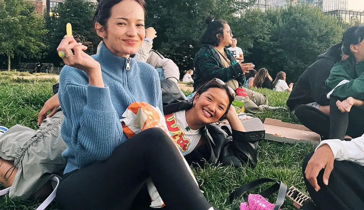 Duduk santai di taman menikmati hari ala Enzy Storia. Dengan atasan turtleneck rajut berwarna biru, dipadu dengan legging panjang berwarna hitam, gaya kasual Enzy dilengkapi dengan sunglasses, kaus kaki panjang, dan sneakers putih. Foto: Instagram.