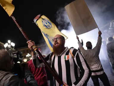 Pendukung Juventus merayakan gelar juara Liga Serie A Italia di Turin (13/5). Juventus bermain imbang 0-0 atas Roma dan memastikan tim asuhan Massimiliano Allegri meraih scudetto. (AFP Photo/Marco Bertorello)