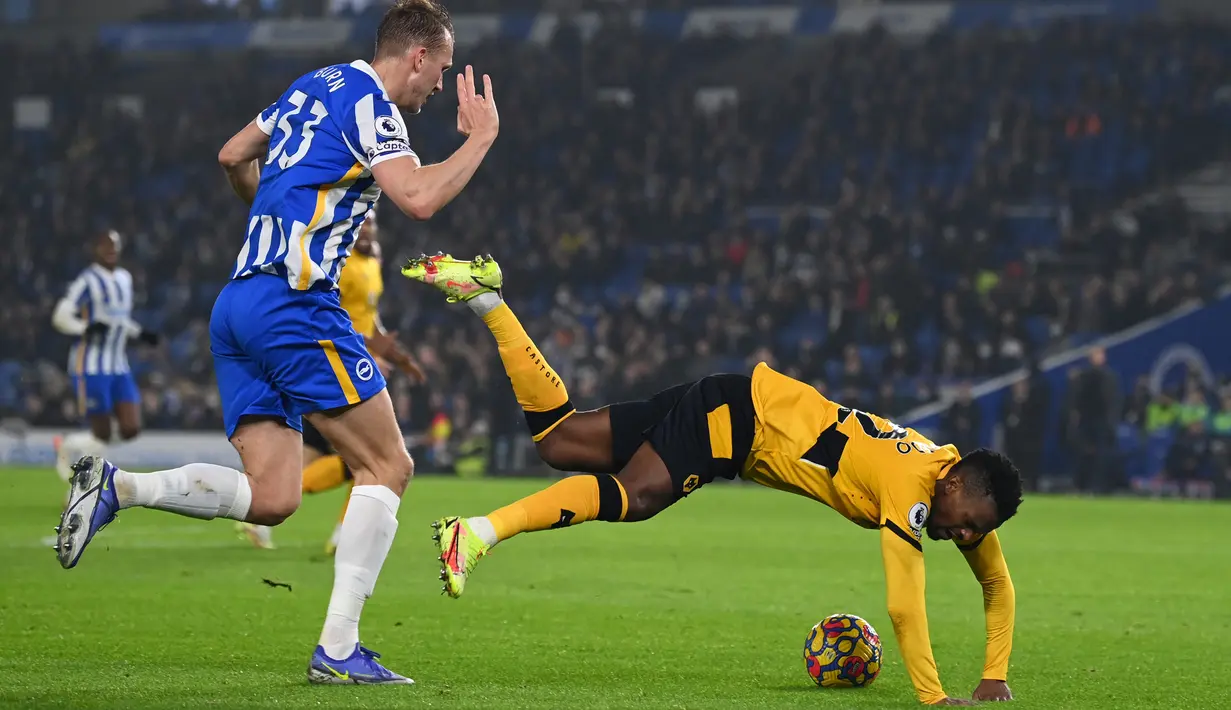 Bek Wolverhampton Wanderers, Nelson Semedo (kanan) berebut bola dengan bek Brighton & Hove Albion, Dan Burn pada laga pekan ke-17 Liga Inggris di Stadion Amex, Kamis (16/12/2021) dini hari WIB. Wolves mengalahkan Brighton & Hove Albion dengan skor 1-0. (Glyn KIRK / AFP)
