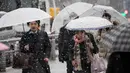 Warga menggunakan payung berjalan selama hujan salju lebat di Tokyo (22/1). Hujan salju membuat keberangkatan penerbangan dan melumpuhkan beberapa layanan kereta api di kota tersebut. (AFP Photo/Behrouz Mehri)