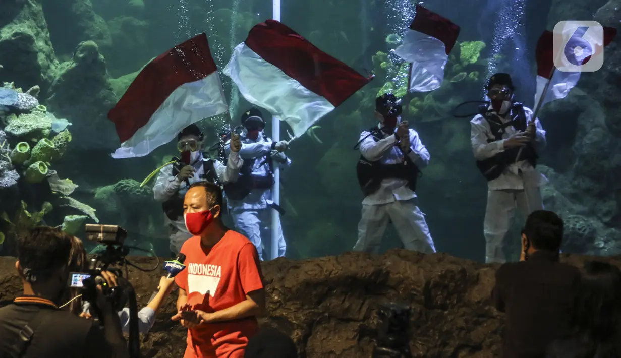 Penyelam mengibarkan bendera Merah Putih saat gladi resik HUT ke-75 RI dalam akuarium Sea World Ancol, Jakarta, Sabtu (15/8/2020). Taman Impian Jaya Ancol akan memperingati HUT ke-75 RI dengan mengibarkan bendera Merah Putih dalam akuarium Sea World pada 17 Agustus 2020. (Liputan6.com/Johan Tallo)