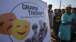 Sejumlah pengungsi Rohingya menonton hiburan dari kelompok teater Drama Therapy di kamp pengungsi Kutupalong, Bangladesh (28/10). (AFP Photo/Tauseef Mustafa)