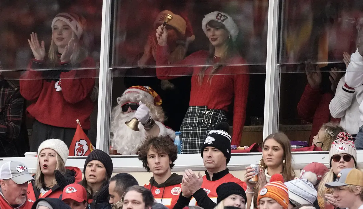 Taylor Swift memberikan dukungan untuk sang kekasih, Travis Kelce saat pertandingan NFL (National Football League) antara Kansas City Chiefs melawan Las Vegas Raiders di Arrowhead Stadium, Kansas, Amerika Serikat, Selasa (26/12/2023) WIB. Ia terlihat mengenakan busana bernuansa natal dengan memadukan sweater merah, plaid miniskirt, dan topi Santa Klaus bertuliskan 87. (AP Photo/Charlie Riedel)