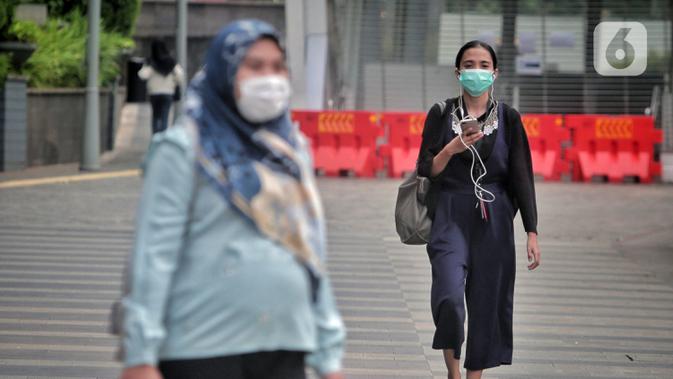 Pegawai pulang kerja berjalan di trotoar Jalan Sudirman, Jakarta, Selasa (12/5/2020). Pemerintah memberi kelonggaran bergerak bagi warga berusia di bawah 45 tahun untuk mengurangi angka pemutusan hubungan kerja (PHK) akibat pandemi virus corona COVID-19. (Liputan6.com/Johan Tallo)