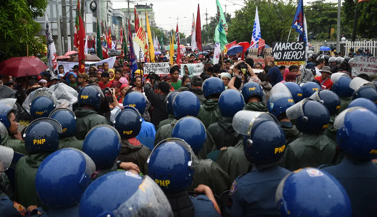 Polisi anti huru hara memblokir para demonstran saat ulang tahun Ferdinand Marcos ke-100 di Manila (11/9). Perayaan ini dihadiri pejabat pemerintah, diplomat, kerabat dan teman-teman dari mantan Presiden Ferdinand Marcos. (AFP Photo/Ted Aljibe)