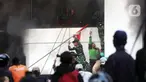 Personel Tentara Nasional Indonesia (TNI) bersama warga membantu mengeluarkan salah satu penghuni gedung yang terbakar di kawasan Kwitang, Jakarta Pusat, Jumat (29/8/2025). (Liputan6.com/Helmi Fithriansyah)