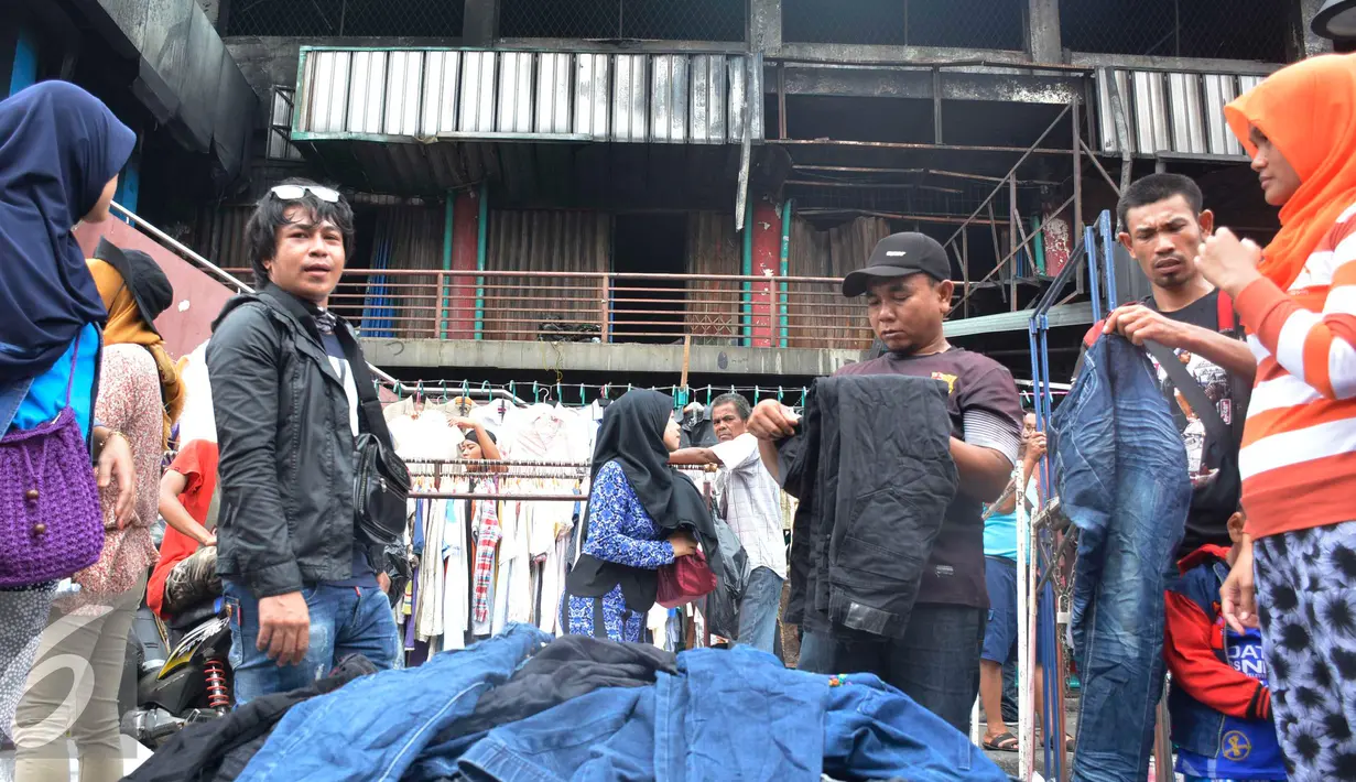 Calon pembeli melihat barang dagangan di depan gedung Pasar Senen pasca kebakaran, Jakarta, Minggu (22/1). Akibat kebakaran yang melanda Pasar Senen pada tanggal 19 Januari lalu, kini pedagang menjual pakaian di bahu jalan. (Liputan6.com/Helmi Affandi)