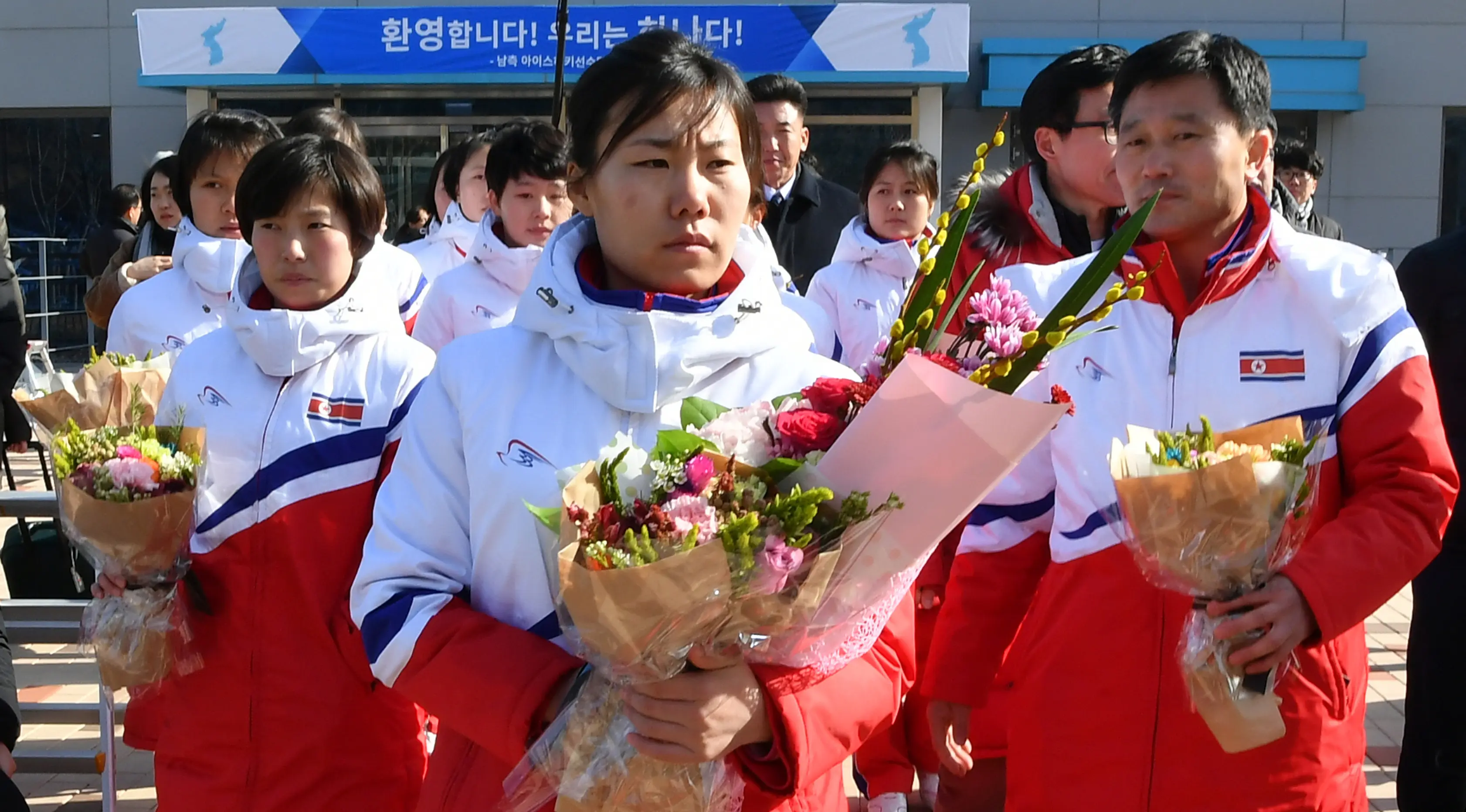 Anggota tim hoki es Korea Utara memegang bunga saat tiba di pusat pelatihan nasional Jincheon, Korsel (25/1). Korea Utara mengirim 12 pemain hoki es untuk mengikuti Olimpiade Musim Dingin PyeongChang di Korea Selatan. (AFP Photo/Pool/ Kyung-Seok)